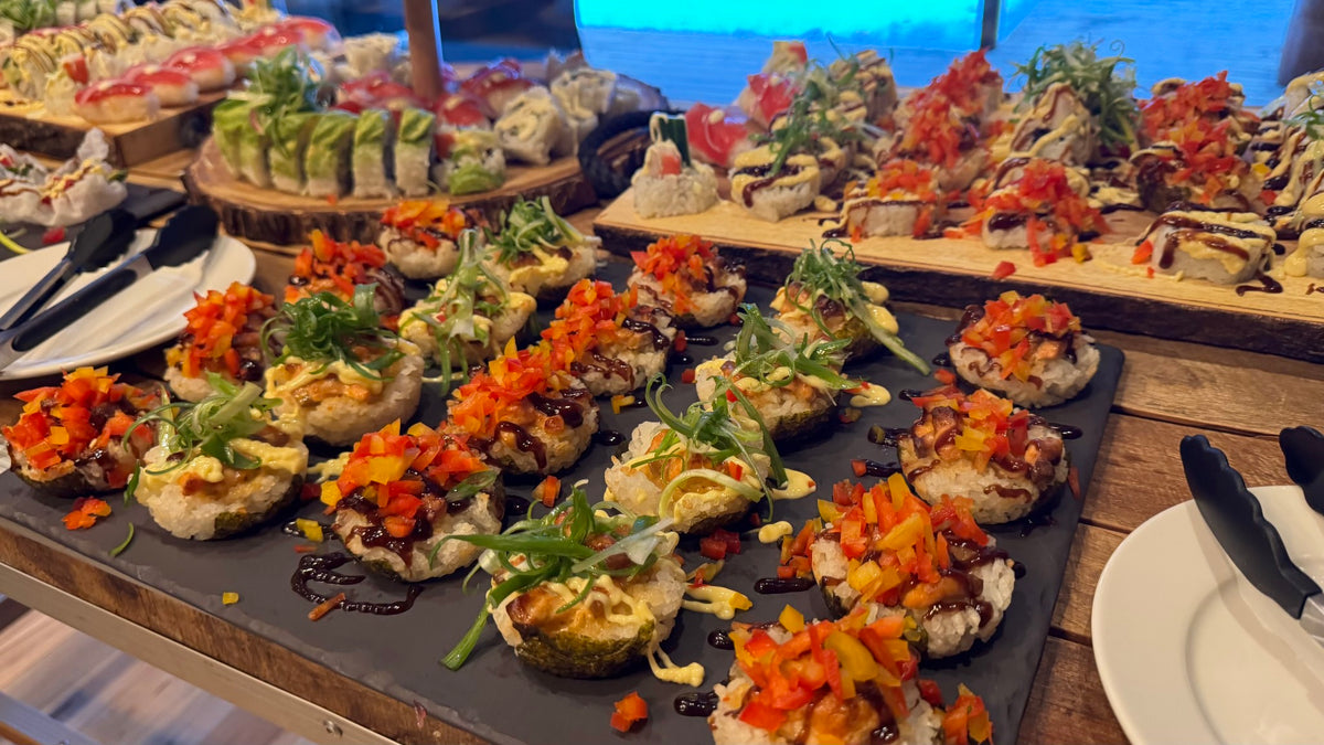 Färgstark sushi med grönsaker och såser på fat för sportfiskare, redo efter fiskeäventyr. Bestick och tallrikar på träbord.