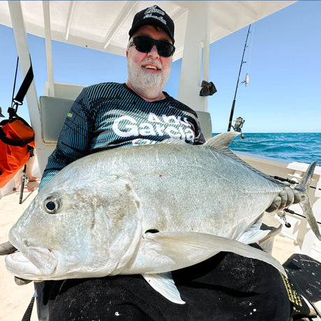 Fiskeresa Madagaskar. Leende sportfiskare med solglasögon och keps håller stor fisk på båt, fiskeutrustning med Outside Travels