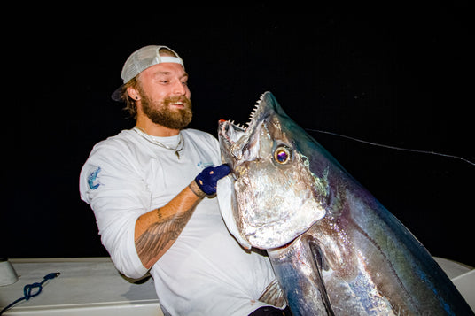 Douglas Dahlberg håller upp en dogtooth tuna fångad på natten med Outside Travels