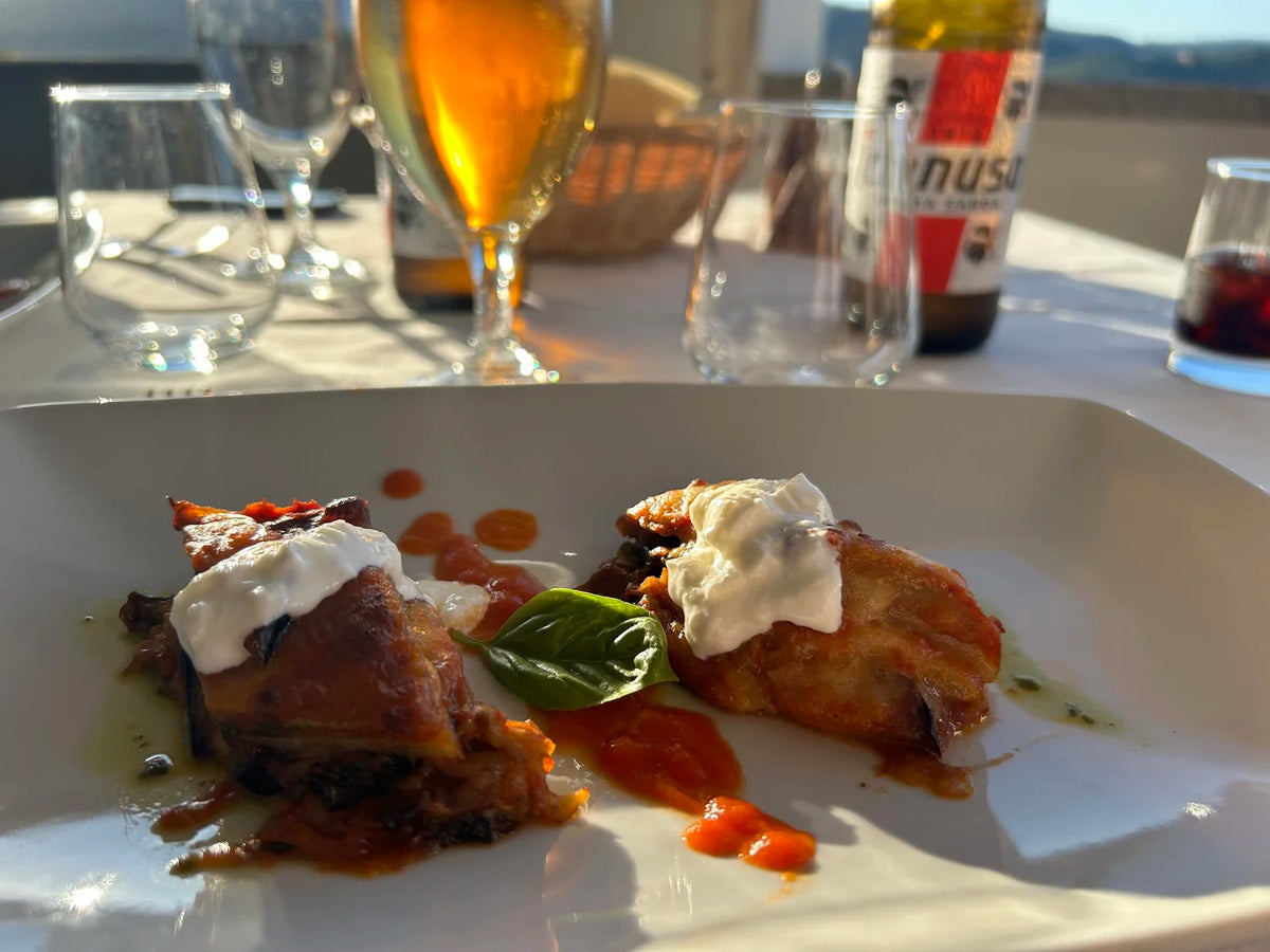 Två bakade aubergineskivor med vit ost och sås på vit tallrik, serveras med basilika-idealisk rätt efter fiskeresan.