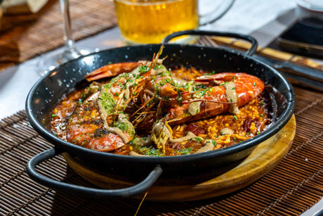 Paella med grillade räkor i en svart paellapanna – middag under fiskeresan i Spanien
